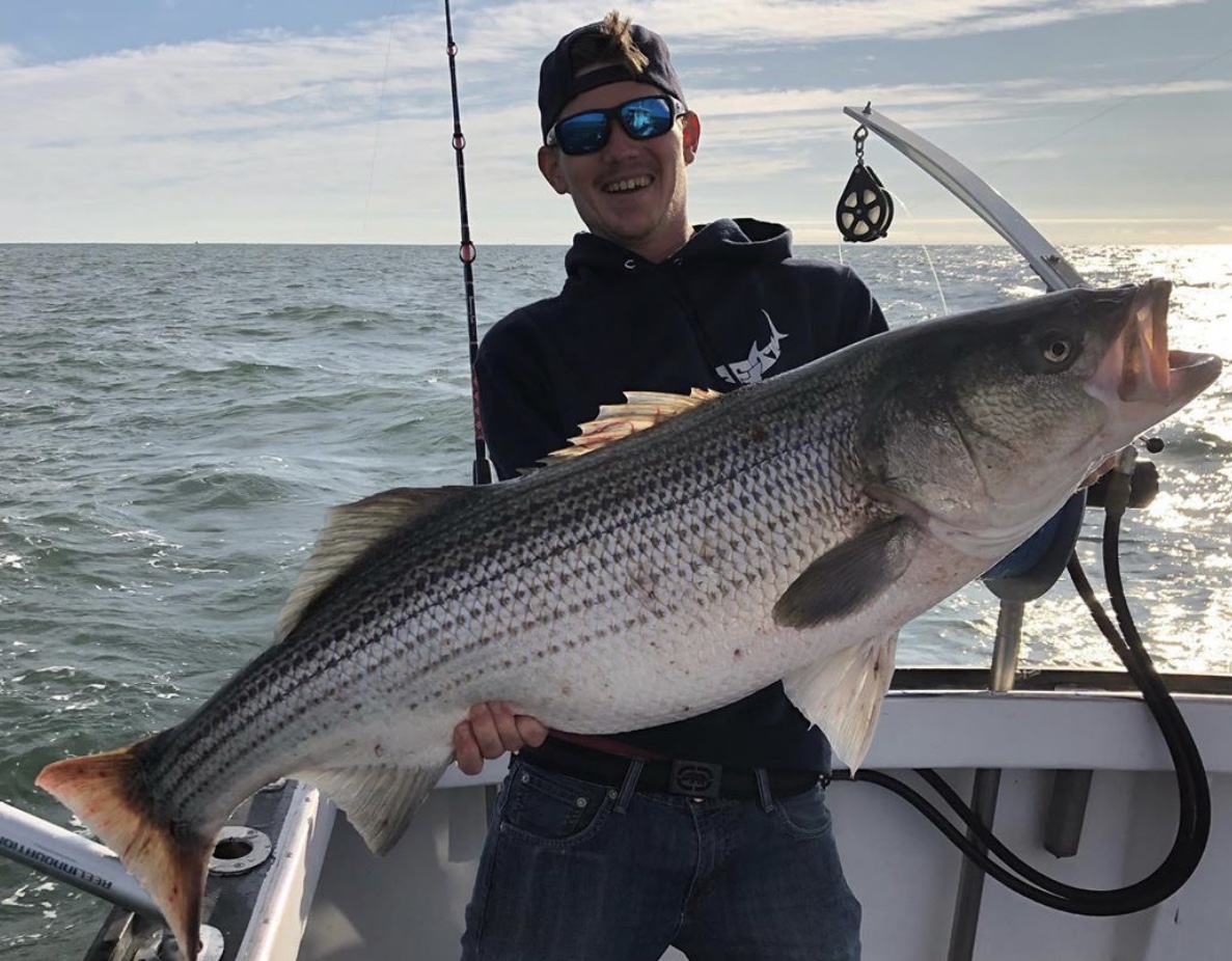 A man holding a large fish on the boat.